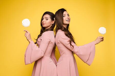 Charming twins eyes with lollipops and posingの写真素材