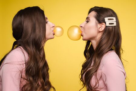 Young twins holding pink and white balloons in their hands.の写真素材