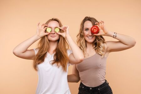 Two healthy women keeping cucumber and appleの写真素材