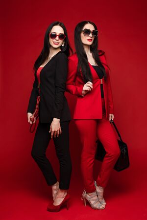 Brunettes in smart suits and glasses standing back to backの写真素材