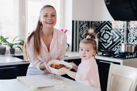 Beautiful woman with lovely child holding bowl with cookies.の写真素材