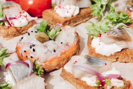Delicious canapes with herring.Macro of delicious canape or sandwiches with fresh herring, black sesame, cream cheese on crispy bread.の写真素材