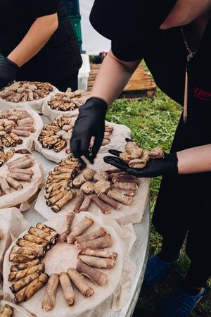 Belaris Minsk 26 07 2019 Workers preparing rolls for catering.Employees in black uniform serving aubergine veggie rolls on round platters for special event, wedding, catering, ceremony.のeditorial素材