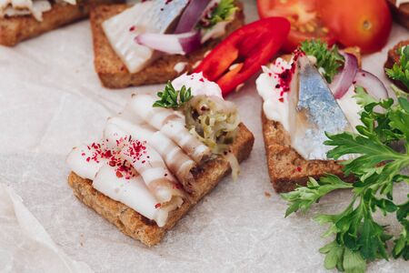 Delicious canapes with herring.Macro of delicious canape or sandwiches with fresh herring, black sesame, cream cheese on crispy bread.の写真素材