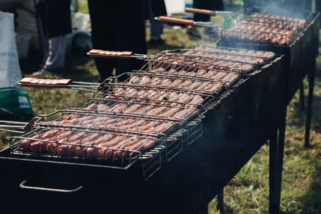 Heap of fresh appetizing sausage cooking on barbecue grill ready for outdoor picnic top viewの写真素材