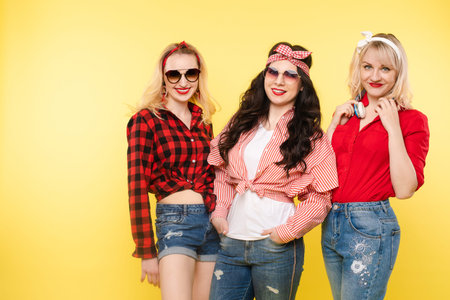 Three stylish and trendy girlfriends.Studio shot of trendy girls with head bows, sunglasses wearing...