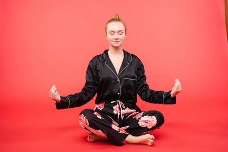Young girl sitting on floor and meditating with closed eyes.の写真素材