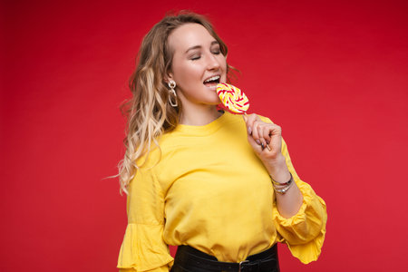 Pretty woman eating delicious candy on stick.