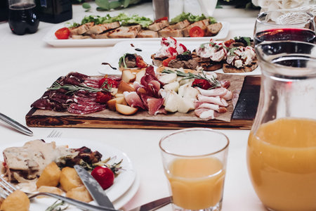 View over wedding reception with cold meat platter, fruit and berry juice and plates with main dish.