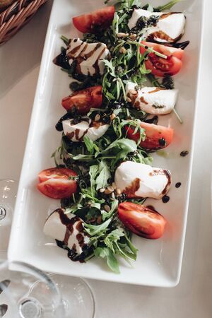 From above view of sliced fresh tomatoes, parsley and cream cheese mascarpone topped with balsamic sauce.の写真素材