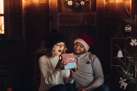 Happy couple under snowfall looking at magical present.