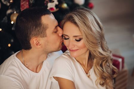 Loving boyfriend kissing girlfriend near Christmas tree.の写真素材