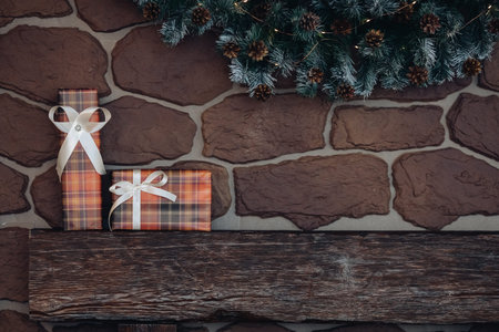 Wrapped Christmas presents on wooden pile. top of a fireplace under Christmas wreath.