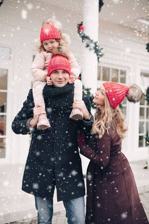 Happy family feeling positive emotion outdoor posing at Christmas design building backgroundの写真素材