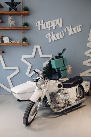 Stock photo of white motorcycle with minuature Christmas tree and wrapped Christmas presents in cradle. Atmospheric interior for Christmas Day. 2020 New Year.の写真素材