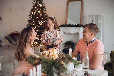 Cheerful girl getting Christmas presents from parents.の写真素材