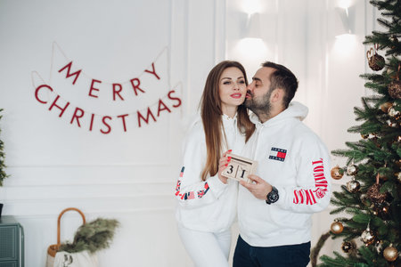 Happy couple kissing enjoying Xmas holiday together having positive emotion