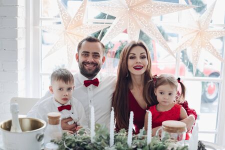 Happy young family sitting at the festive table at homeの写真素材