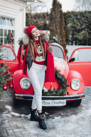 Belarus Minsk 16 12 2019:Pretty smiling woman standing near red car outdoorsのeditorial素材