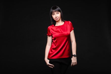 Attractive businesswoman in red stylish clothing posing isolated at black studio backgroundの写真素材