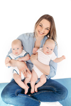 Beautiful young mother sits on the floor with her children and smiles
