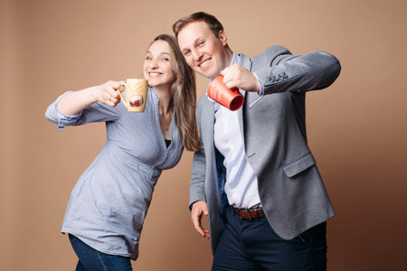 Two beautiful lovers stands with cups and smiles