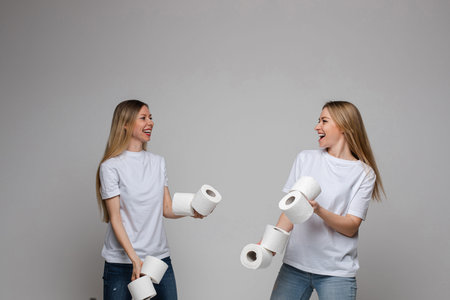 Smiling cheerful women playing with toilet paper.