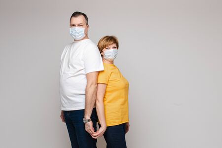 A couple in love hugs together and stands in medical masks, portrait isolateed on white backgroundの写真素材