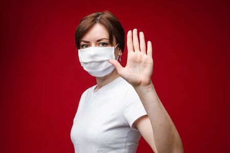 Young woman in protective suit making gesture protection by hand in glove medium close upの写真素材