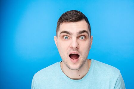 Surprised young guy is posing in studioの写真素材