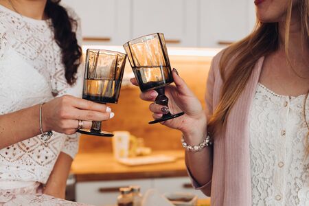 Two caucasian girls drinks water with glasses in the kitchen togetherの写真素材
