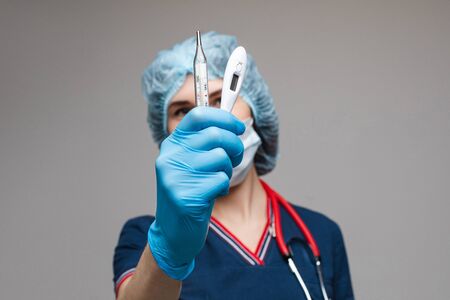 Portrait of female doctor in medical clothes with phonendoscope around her neck holds several test tubes, picture isolated on white backgroundの写真素材