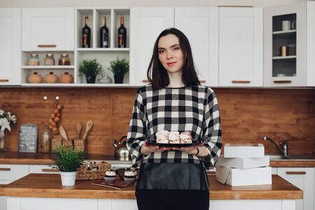 Attractive woman made marshmallows, put them in a box and shows it in her big bright kitchenの写真素材
