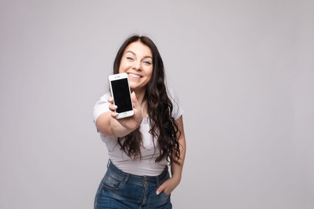 Pretty girl pointing at cell phone.Studio portrait of beautiful caucasian