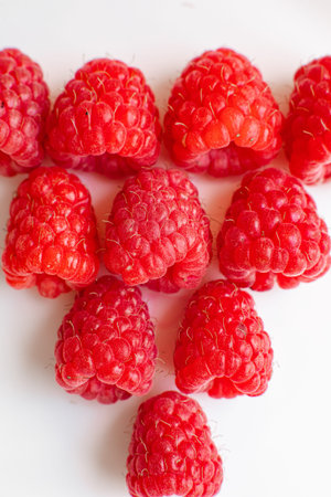 Beautiful raspberries in triangle shape lies isolated on a white background. Cut out, close up....