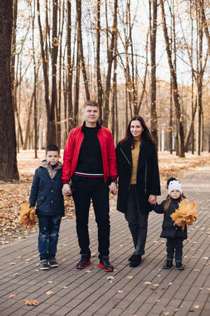 Caucasian family goes for a walk in the autumn park with two childrenの写真素材