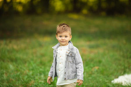Pretty little boy in stylish clothes walks outsideの写真素材