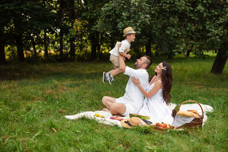 Beautiful mum, dad and their cute little child have fun together and smiles outsideの写真素材