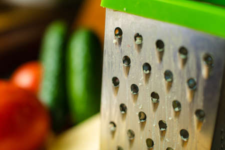Picture of metal kitchen grater with oval holes on it on the kitchen tableの写真素材