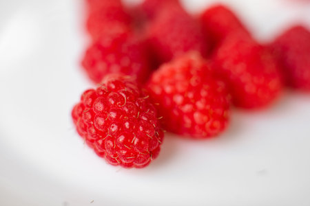 A picture of a few raspberries lies on a white background. Background and picture for postcard