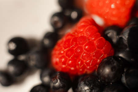 Many juicy fresh ripe red raspberry berries with blackberries isolated on white backgroundの写真素材