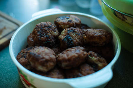 Plenty of ready-made fried meatballs lie in a large white aluminum pan on the tableの写真素材
