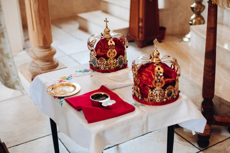 Two beautiful crowns with gold and red cloth stand on a table in the church before the baptism of...