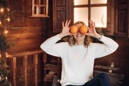 Young funny girl in warm clothes having fun with orangesの写真素材