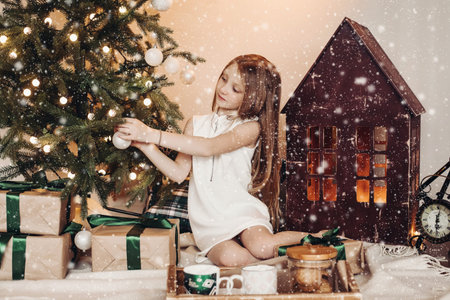 Girl decorating Christmas tree under snow.