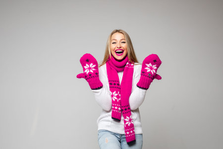 Joyous blonde lady puttting hands in new mittens up
