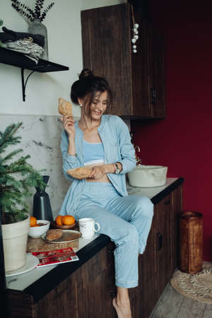 Cheerful brunette woman holding pastries in the kitchenの写真素材