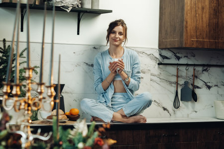 Mirthful young woman sitting cross-legged on tabletop