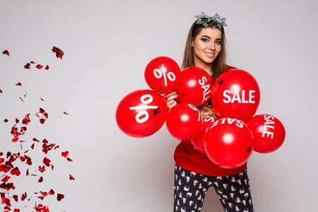beautiful caucasian woman with a lot of red baloons with sales and percents on them