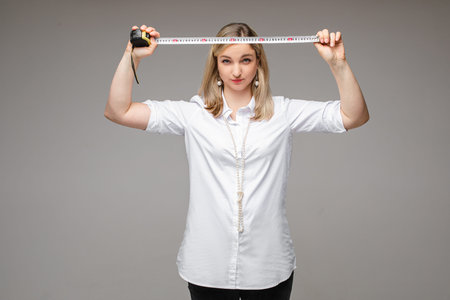 Confident lady in white shirt posing with tape measure